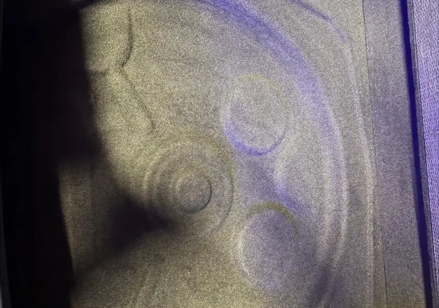 Gros plan sur le compartiment de roue de secours du coffre d’un Volkswagen Tiguan gris, intérieur vide et propre.