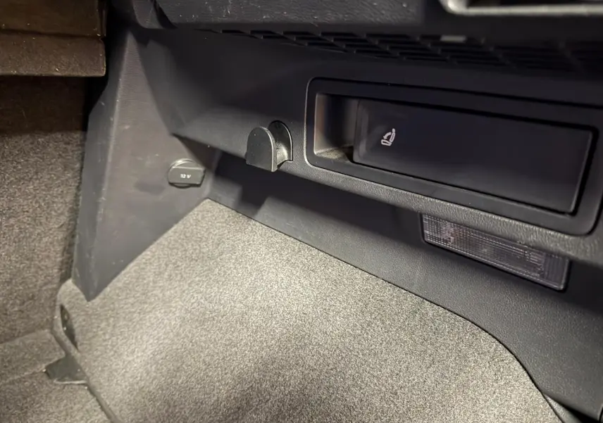 Détail de la console centrale côté passager du Volkswagen Tiguan gris, avec prise 12V et rangement intégré.