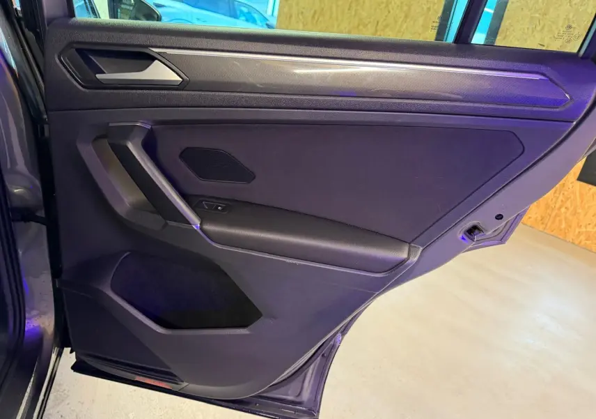 Vue intérieure de la porte arrière droite gris Tungstène du Volkswagen Tiguan 2018 avec accoudoir et commande de vitre électrique.