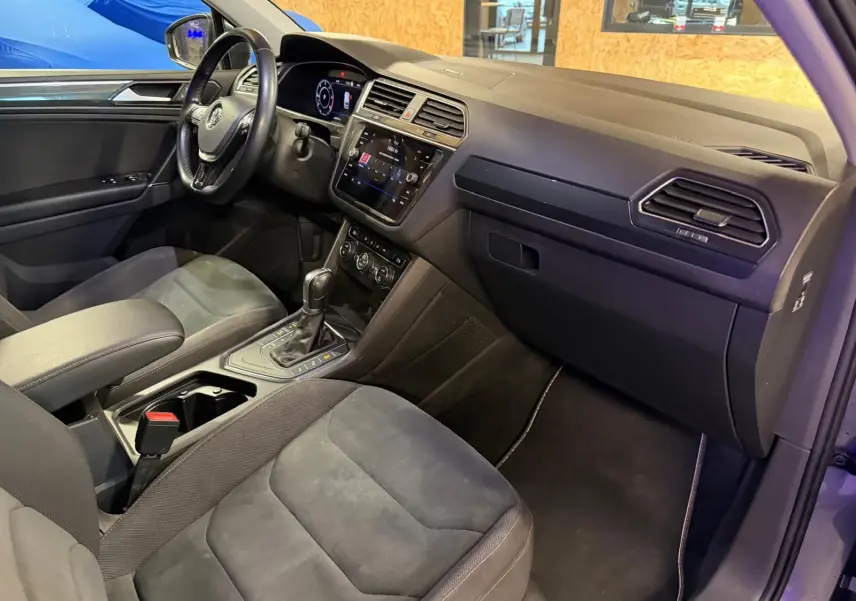 Vue intérieure côté passager du Volkswagen Tiguan 2018, montrant sièges sport gris et tableau de bord moderne avec écran tactile.