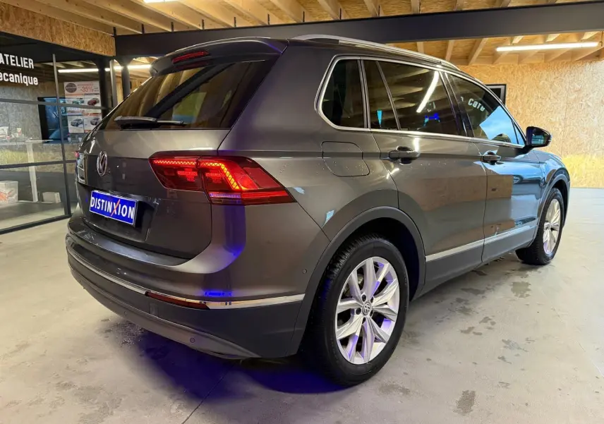 Volkswagen Tiguan gris 3/4 arrière droit en intérieur, avec jantes alu et vitres teintées.