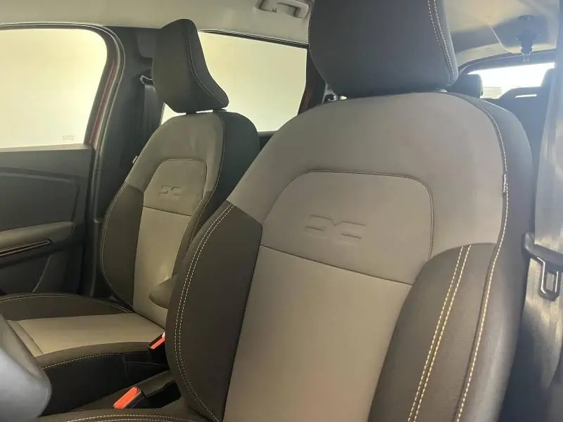 Gros plan sur les sièges avant gris et noirs du Dacia Jogger 2024 avec logo embossé et surpiqûres contrastées.