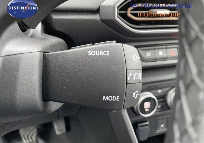 Gros plan sur la commande audio au volant du Dacia Jogger 2024, intérieur noir avec détails de la console en arrière-plan.