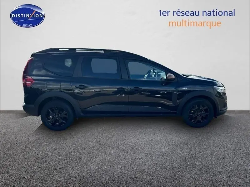 Profil droit du Dacia Jogger 2024 noir nacré métallisé, avec barres de toit et jantes alu noires.