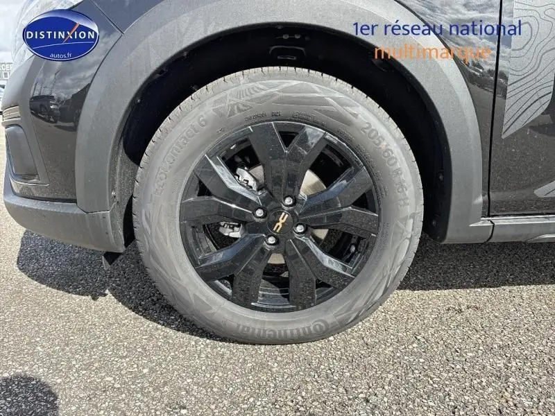 Gros plan sur la roue avant gauche noire nacrée métallisée du Dacia Jogger 2024 avec jante alu noire et logo central doré.