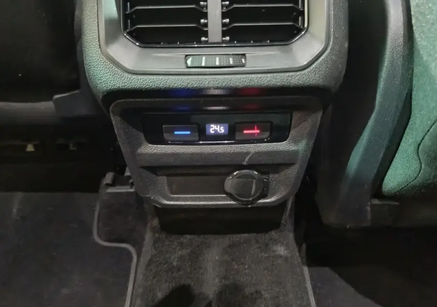 Gros plan sur la console arrière du Volkswagen Tiguan bleu, affichant la climatisation digitale à 24,5°C et une prise 12V.