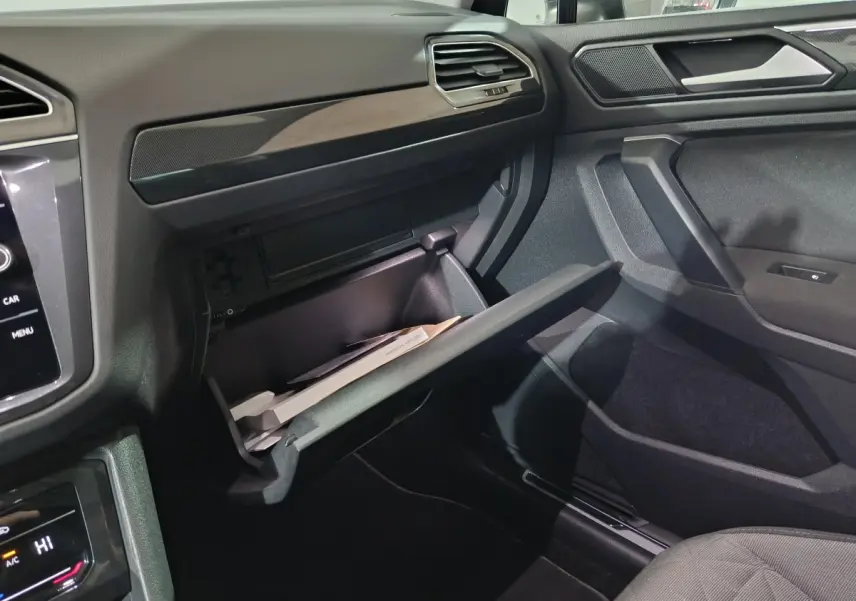 Intérieur côté passager du Volkswagen Tiguan bleu 2021, boîte à gants ouverte avec documents visibles.