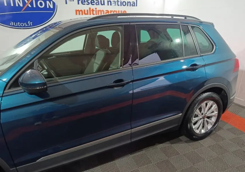 Vue latérale droite du Volkswagen Tiguan bleu 2021 avec jantes alliage et rétroviseurs intégrant clignotants.