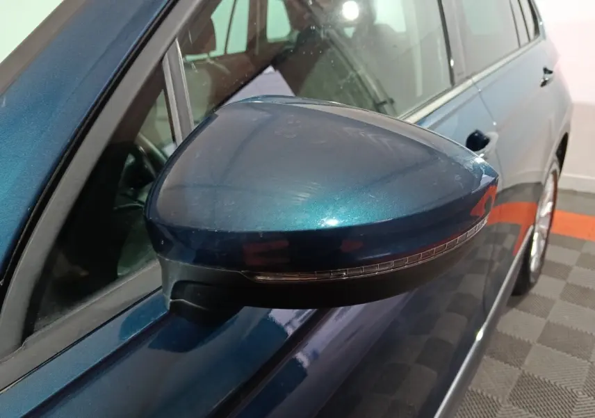 Rétroviseur côté gauche bleu métallisé du Volkswagen Tiguan 2021, avec clignotant intégré, vue rapprochée en intérieur.