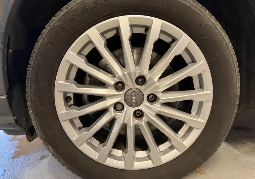 Gros plan sur la jante alu argentée d'un Audi Q2 gris, mettant en valeur le logo Audi au centre.