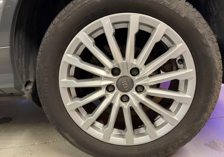 Gros plan sur la jante alu argentée d'une Audi Q2 gris, mettant en valeur le logo Audi au centre.
