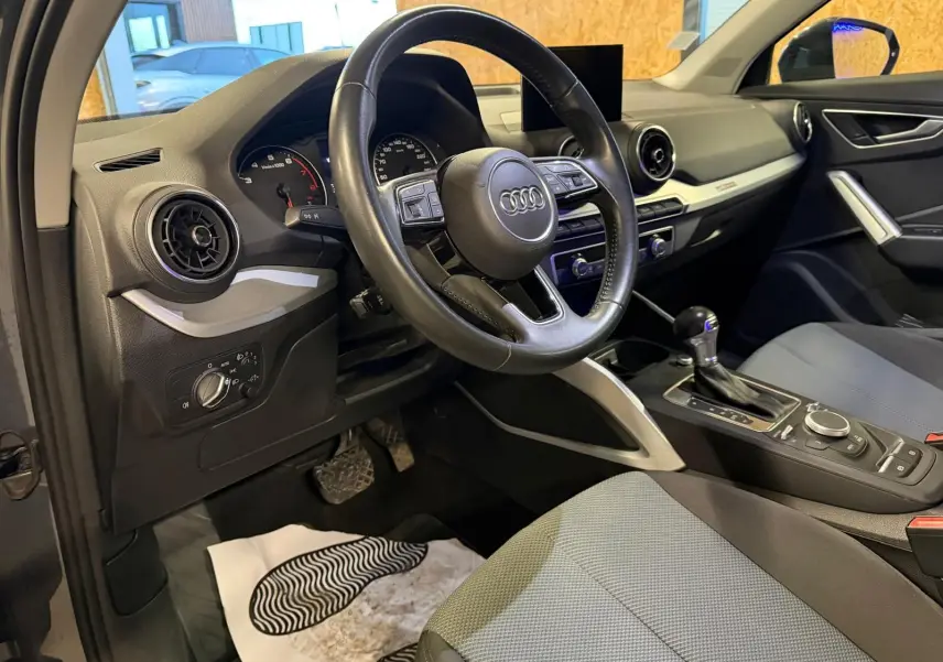 Vue intérieure côté conducteur de l'Audi Q2 2018, volant cuir multifonctions et console centrale avec boîte auto.