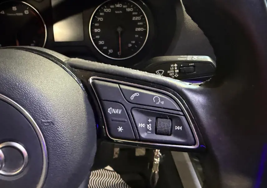 Gros plan sur le volant cuir multifonctions côté droit de l’Audi Q2 1.0 TFSI gris avec commandes audio et navigation.