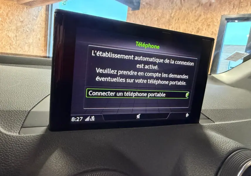 Écran multifonction affichant la connexion Bluetooth dans l'habitacle d'une Audi Q2 gris, vue de face rapprochée.