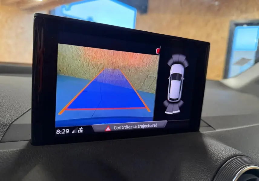 Écran intérieur montrant la caméra de recul et l’aide au stationnement du tableau de bord de l’Audi Q2 gris.