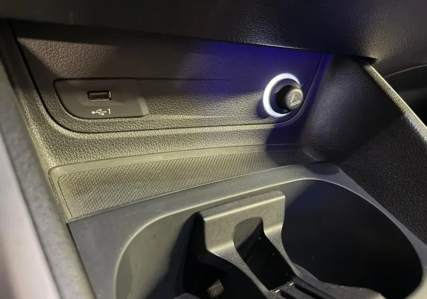 Gros plan sur la prise USB et l’allume-cigare dans l’espace de rangement noir de l’Audi Q2 gris.