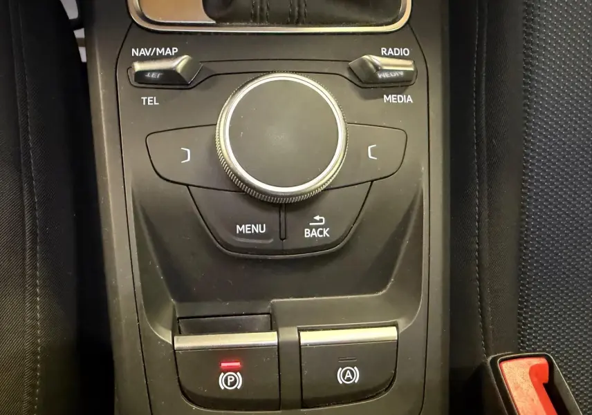 Vue rapprochée de la console centrale noire de l'Audi Q2 avec molette de contrôle et boutons de frein à main et auto-hold.