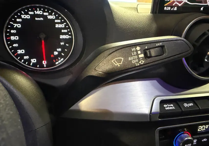 Détail intérieur du tableau de bord gris de l'Audi Q2 2018, avec compteur vitesse et commande essuie-glace.