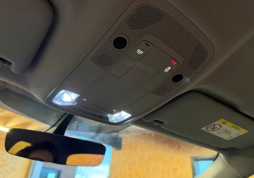 Plafonnier intérieur allumé avec commandes et rétroviseur central dans un Audi Q2 gris, vue de l'habitacle vers le toit.