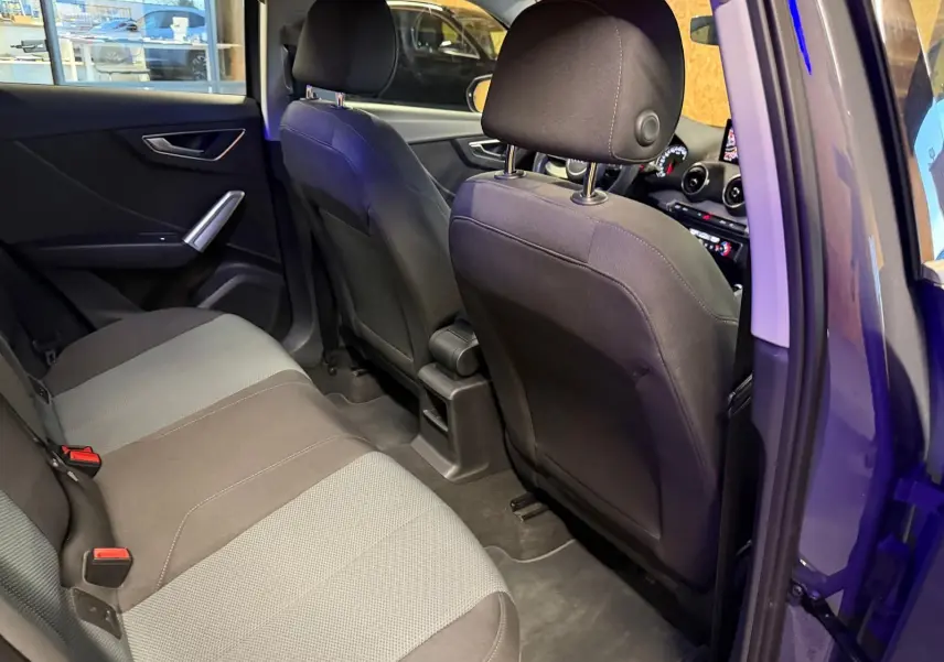 Vue intérieure arrière côté gauche de l'Audi Q2 2018, montrant les sièges tissu bicolore et la portière ouverte.