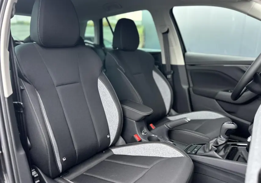 Vue intérieure rapprochée des sièges avant noirs et gris du Skoda Kamiq 2025 avec console centrale et levier de vitesse.