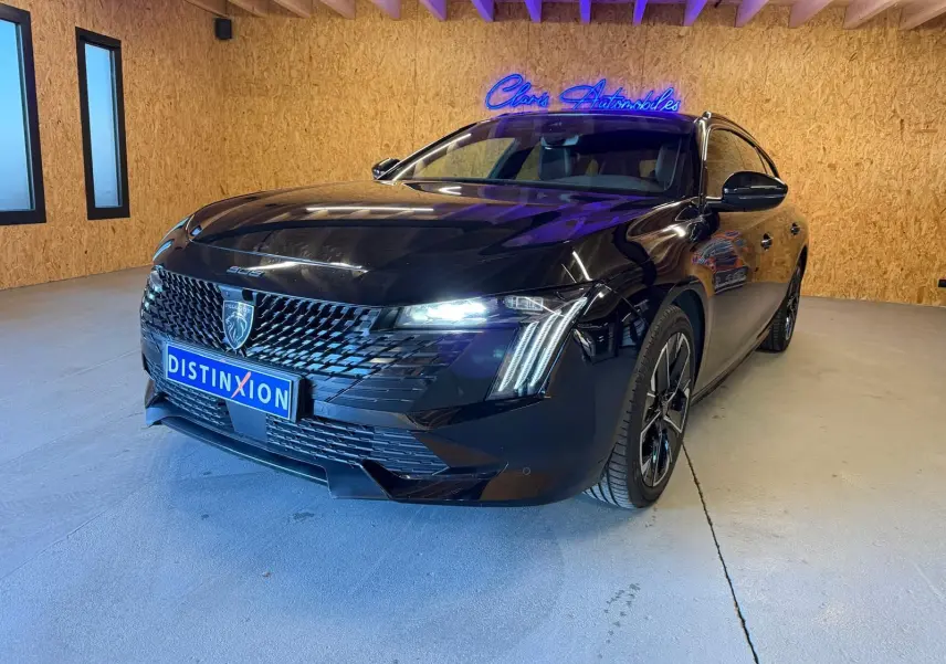 Peugeot 508 SW noire vue 3/4 avant droit avec calandre noire brillante et feux LED allumés en intérieur.