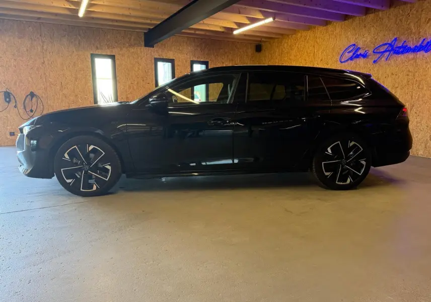 Peugeot 508 SW noire vue de profil côté gauche, avec jantes alliage bi-ton et toit noir brillant.
