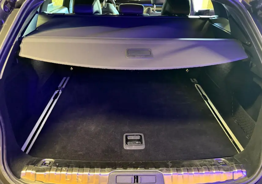 Coffre ouvert d’un Peugeot 508 SW noir, vue arrière montrant la plage arrière et le tapis de coffre noir.