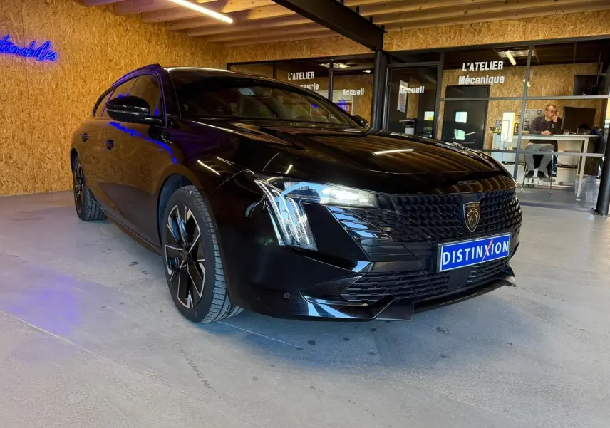 Peugeot 508 SW noire vue 3/4 avant droit, avec calandre noire brillante et jantes alliage bi-ton diamantées.