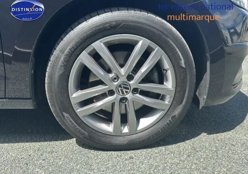 Gros plan sur la roue avant gauche avec jante alu argentée du Volkswagen Touran noir 2025.