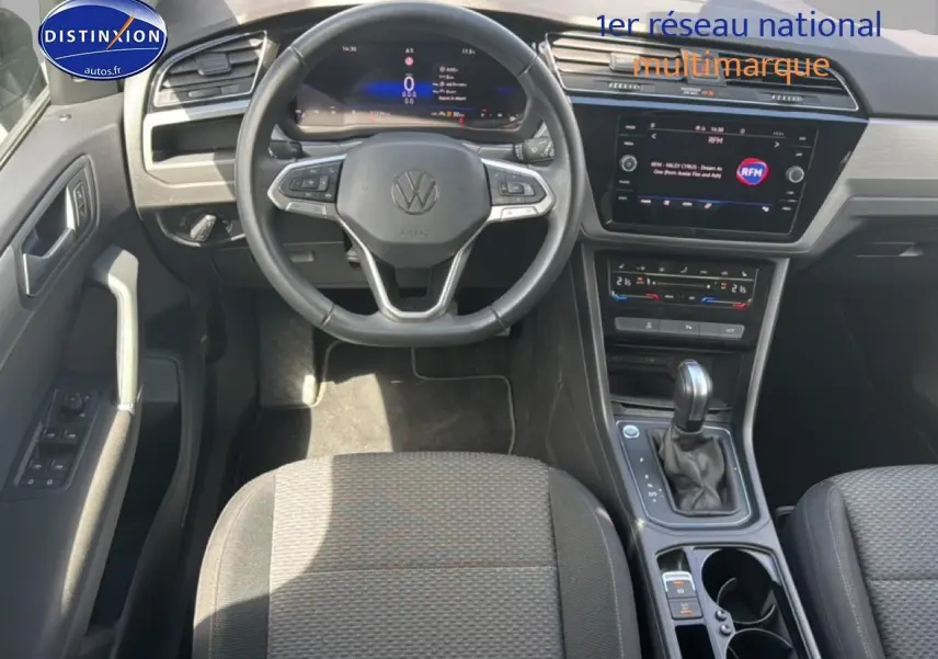 Vue intérieure avant du Volkswagen Touran noir 2025, volant cuir multifonction et écran tactile central visible.