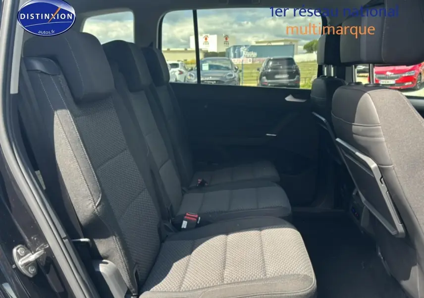 Vue latérale intérieure montrant les sièges tissu gris du rang 2 du Volkswagen Touran noir 2025 avec 7 places.