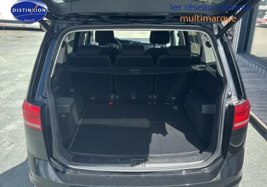 Vue arrière ouverte du coffre noir d’un Volkswagen Touran 2025 avec la troisième rangée de sièges visible.