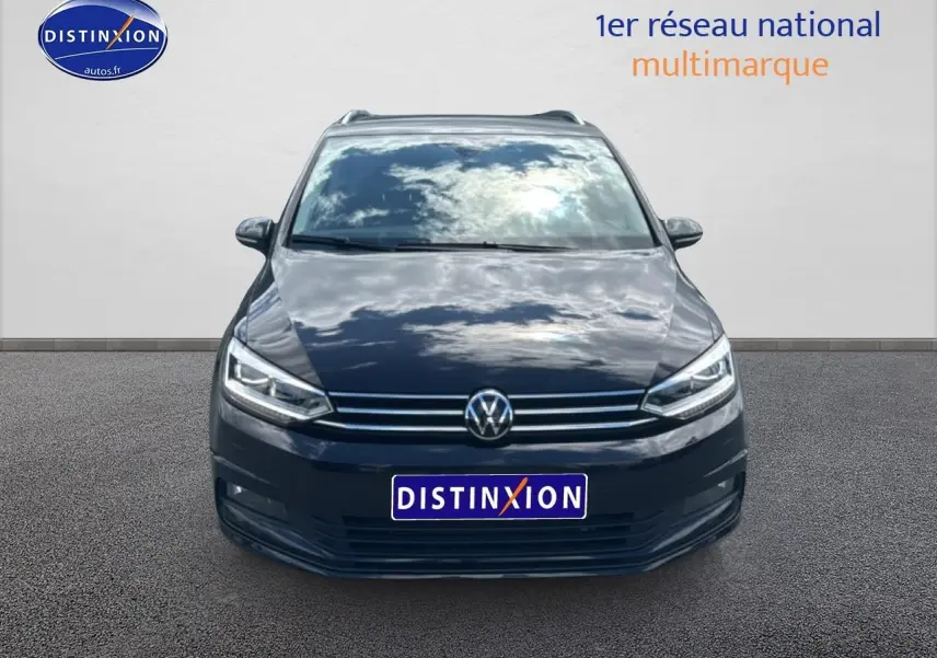 Vue frontale d'un Volkswagen Touran noir 2025 avec calandre chromée et phares LED allumés.