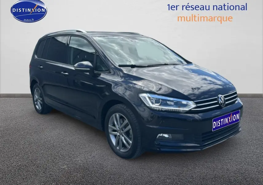 Volkswagen Touran noir 2025 en 3/4 avant droit, avec jantes alu et barres de toit visibles.