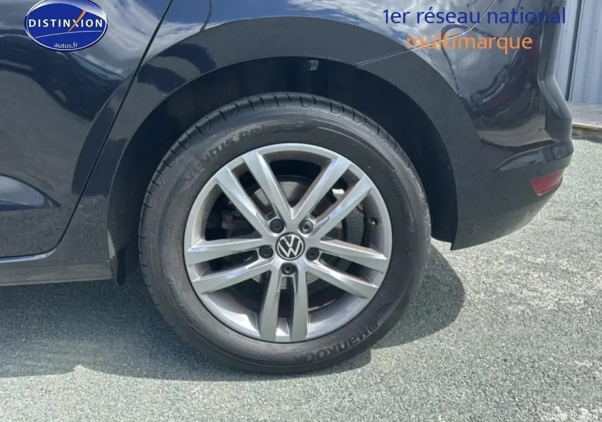 Gros plan sur la roue arrière droite d'un Volkswagen Touran noir avec jante alu cinq branches.