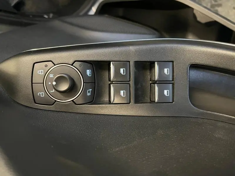 Gros plan sur les commandes de réglage des rétroviseurs et des vitres côté conducteur du Ford Puma gris Solar Métallisée 2021.