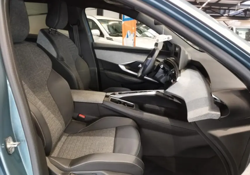 Vue intérieure côté conducteur du Peugeot 5008 bleu Ingaro, montrant sièges tissu et cuir ainsi que planche de bord tissu gris.