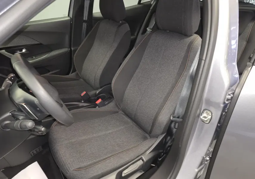 Vue intérieure côté conducteur du Peugeot 2008 gris 2025, sièges tissu gris chiné avec surpiqûres orange.