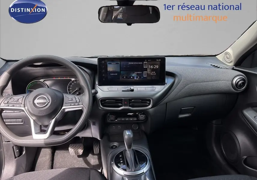 Vue intérieure avant du tableau de bord et volant du Nissan Juke Hybrid 2024 avec écran tactile central et finition noire.