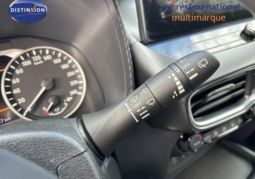 Gros plan sur la commande d’essuie-glace à droite du volant du Nissan Juke gris squale métal 2024, tableau de bord partiellement visible.