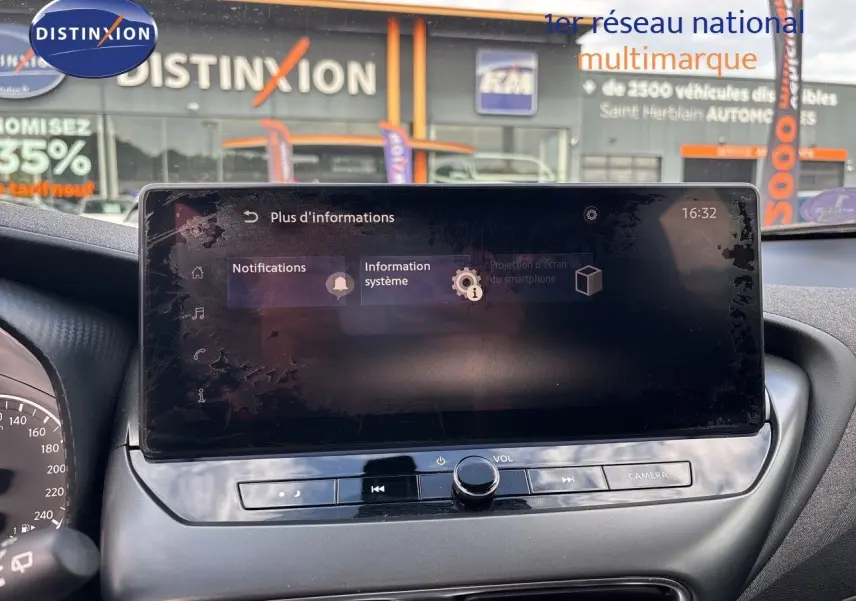 Écran tactile central du Nissan Juke Hybrid 2024 en intérieur, avec commandes audio et caméra visibles.