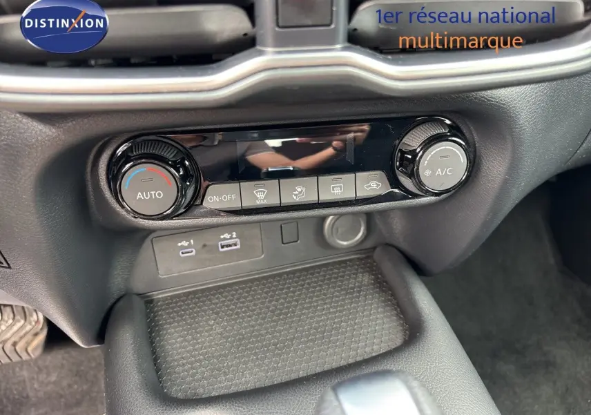 Vue rapprochée de la console centrale du Nissan Juke 2024, montrant les commandes de climatisation et ports USB.