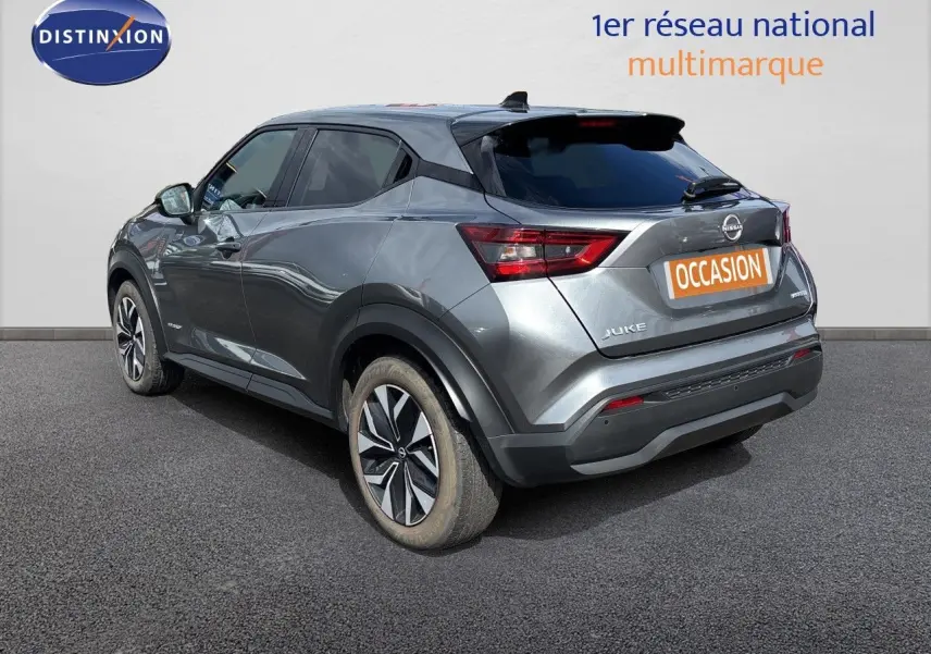 Nissan Juke Hybrid gris squale metal, vue 3/4 arrière droit, avec jantes alliage et vitres teintées.