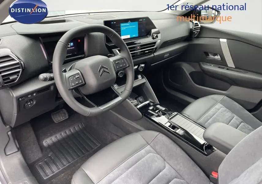 Intérieur avant du Citroën C4 2024 avec tableau de bord moderne, volant multifonction et sièges cuir gris foncé.