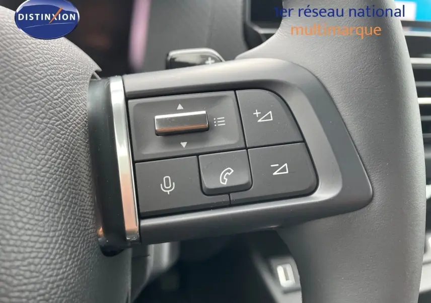 Gros plan sur les commandes au volant à gauche de la Citroën C4 blanche métal 2024, boutons de volume et appel.