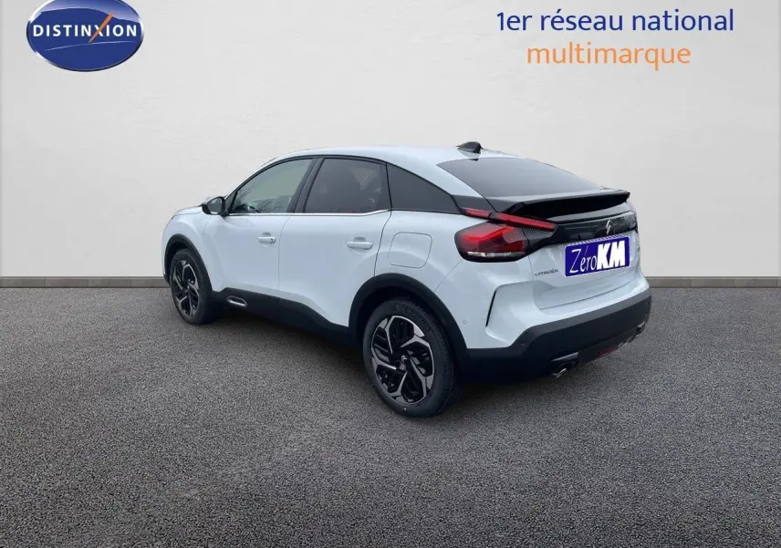 Citroën C4 blanc métal vue 3/4 arrière côté gauche, avec toit noir et jantes bicolores.