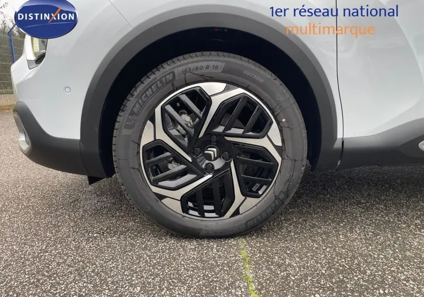 Gros plan sur la roue avant droite d'une Citroën C4 blanche métal avec jante alliage bicolore moderne.