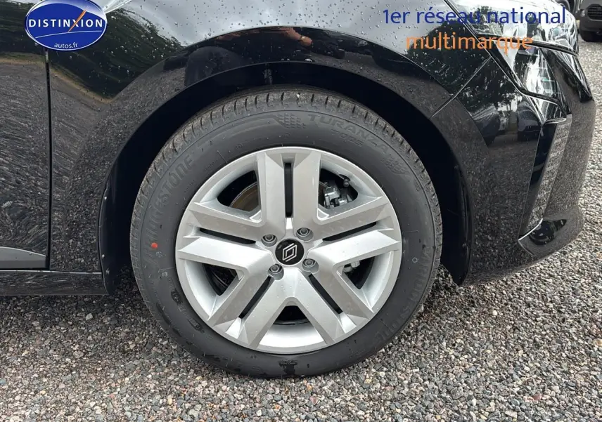 Gros plan sur la roue avant gauche de la Renault Clio V noire avec jante argentée et logo central distinctif.