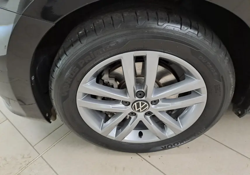 Gros plan sur la roue avant droite d’un Volkswagen Touran noir Grenadille avec jante alliage argentée.